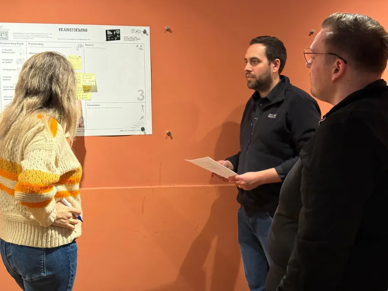 Gespräch vor dem Brainstorming-Plakat an der Wand