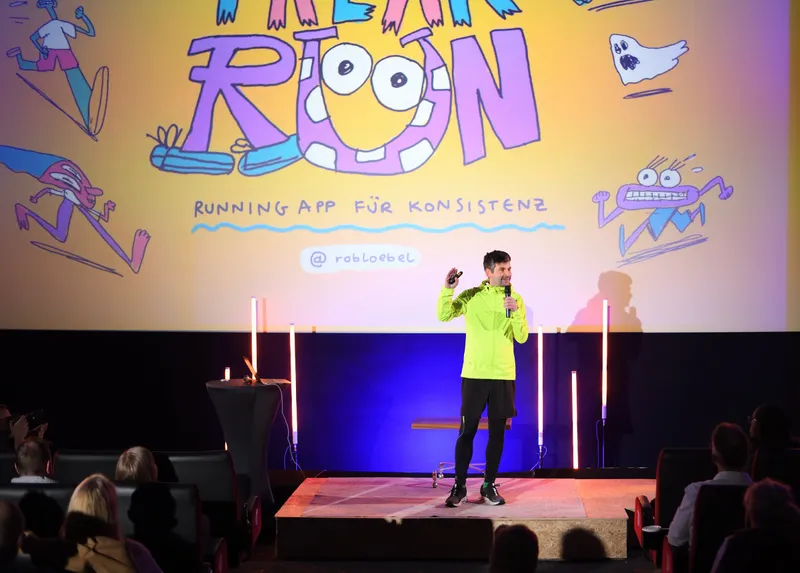Pitch auf der Bühne vor der Leinwand mit der Folie „Running App für Konsistenz“